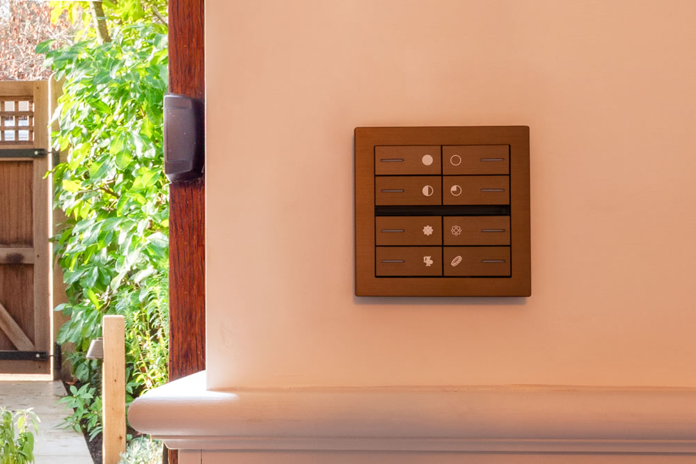 Brushed bronze Eelectron OL-U KNX control panel by the garden door, featuring custom Lord of the Rings engraved icons for integrated smart lighting and garden scenes at AVINU's Northmoor Road heritage project
