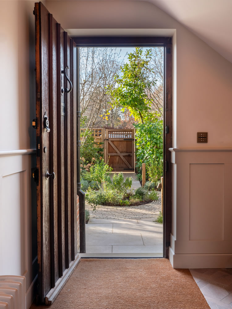 Minimalist AVINU smart home interface located by a garden entrance, featuring custom-engraved buttons for seamless transitions between indoor and outdoor lighting environments