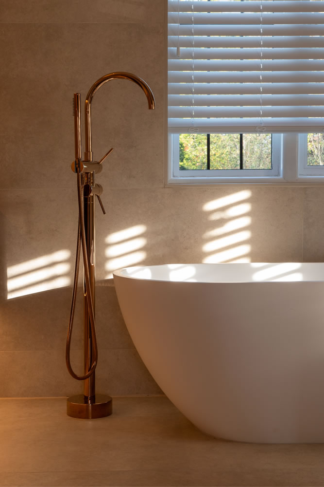 Modern luxury bathroom in the Northmoor smart home project by AVINU, featuring automated window blinds and a freestanding bathtub with sleek designer taps