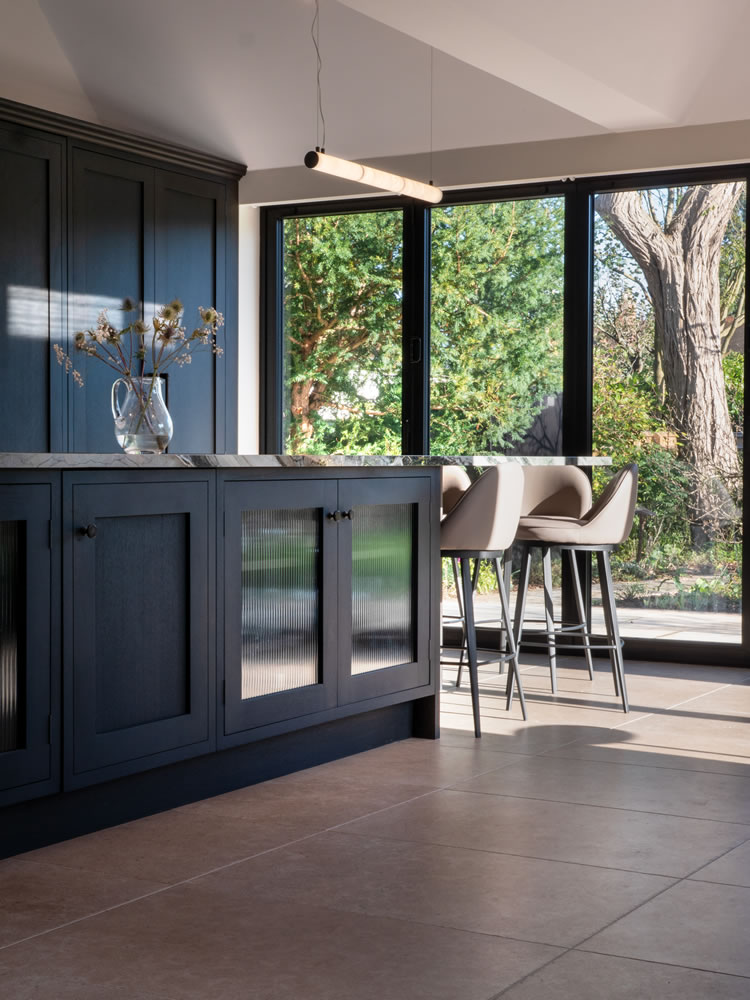 Modern smart kitchen in Northmoor Road project by AVINU, showcasing integrated lighting and floor-to-ceiling windows overlooking the garden